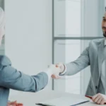 Reclutador y candidata estrechando la mano tras una entrevista de trabajo exitosa